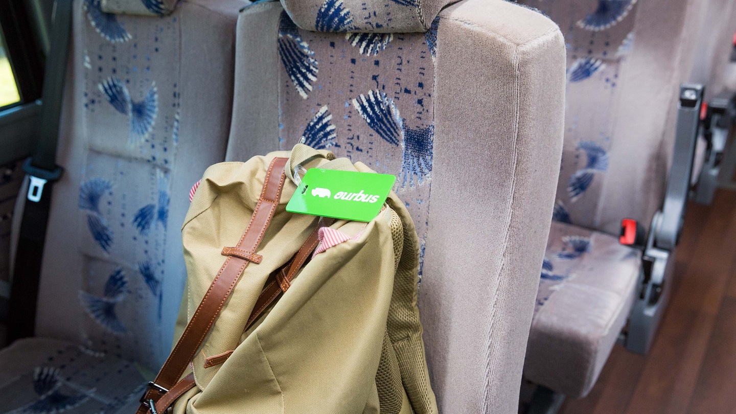 inside of a bus with OurBus branded luggage tag on backpack